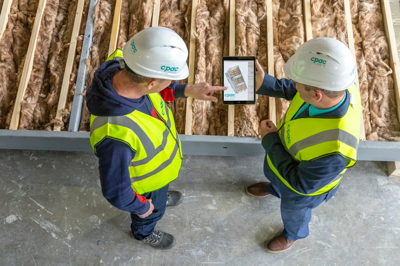 Two engineers reviewing plans on site beside acoustic insulation